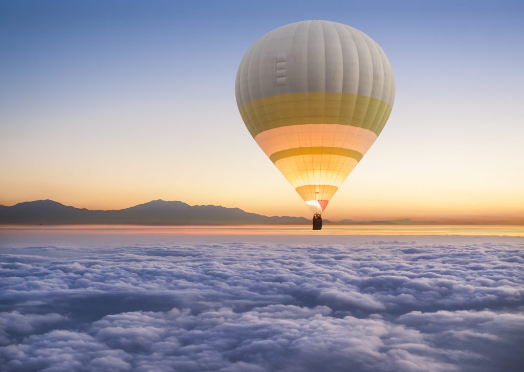 Mongolfiera in volo sopra le nuvole
